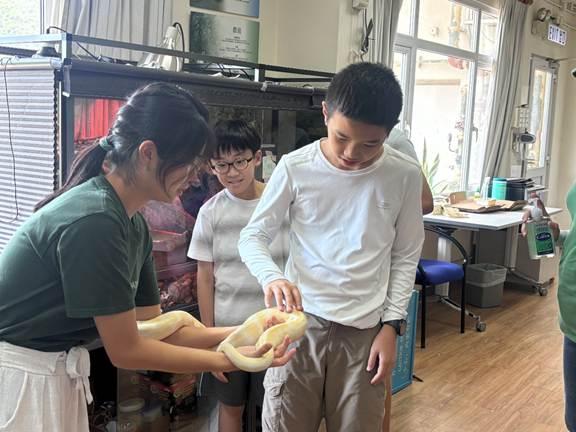A group of people holding a snake
AI-generated content may be incorrect.